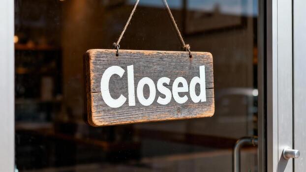 A weathered wooden sign, announcing Closed, hangs from a storefront window. photo