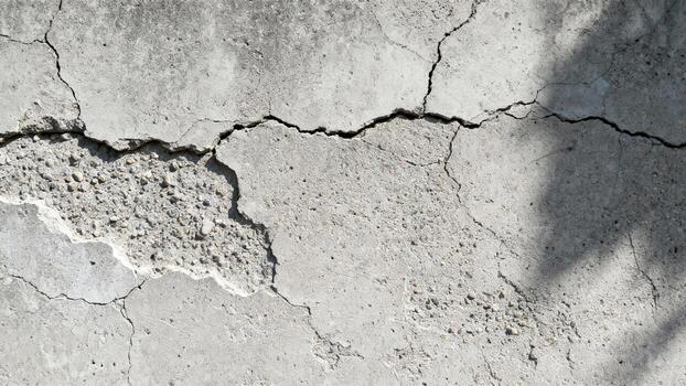 Severe damage featuring deep fissures and exposed aggregate on a weathered concrete surface. photo