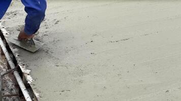 betong glättning i framsteg en hantverkare noggrant slätar ut våt betong med en murslev, en testamente till precision och de rå textur av konstruktion. video