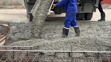 häller betong på konstruktion ett actionfylld scen av betong häller på en konstruktion webbplats, visa upp de dynamisk bearbeta av byggnad en fundament. detta skott funktioner en konstruktion arbetstagare. video