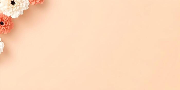 White and coral paper flowers adorn the corner of a soft peach background creating a gentle elegant border with ample copy space photo