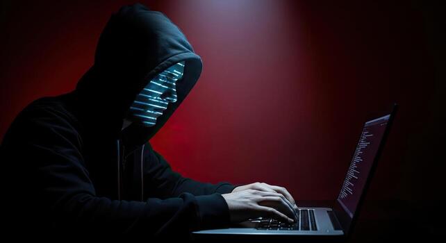 Anonymous Hacker in Hoodie Typing on Laptop Cybercrime Data Breach and Digital Security Threat photo