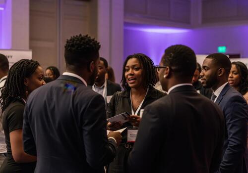 A group of people standing around talking at a conference photo