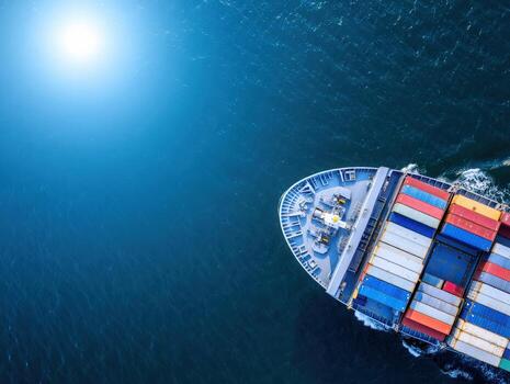 Stunning aerial view of a massive cargo ship transporting colorful containers across a vast, sunlit ocean, symbolizing global trade and logistics in motion. photo