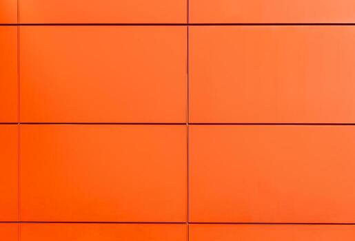 Orange wall with rectangular metal panels creating modern geometric pattern. Minimalist architectural background with clean lines and vibrant colour, ideal for design, construction, abstract concepts photo