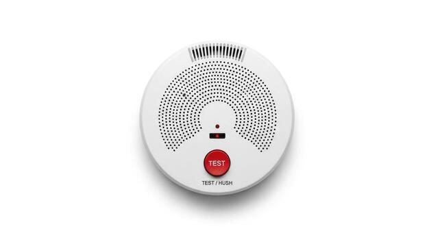 White smoke detector with red test button isolated on white background photo