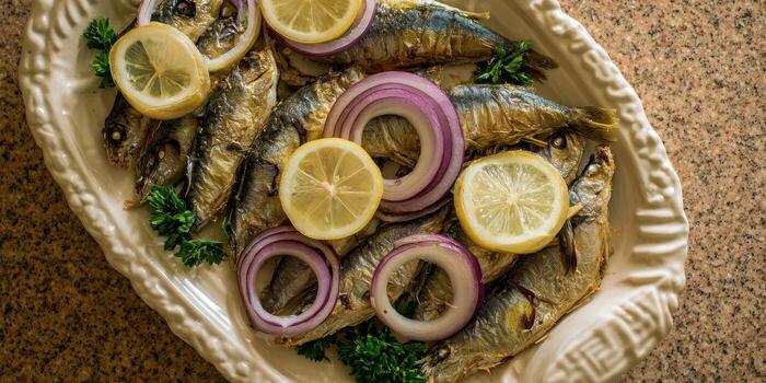 Grilled fish with onion rings and lemon slices on a decorative plate photo
