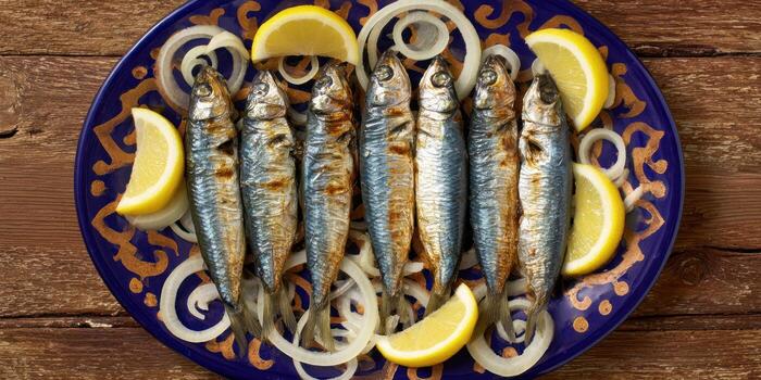 Grilled sardines with lemon and onion served on a decorative plate photo