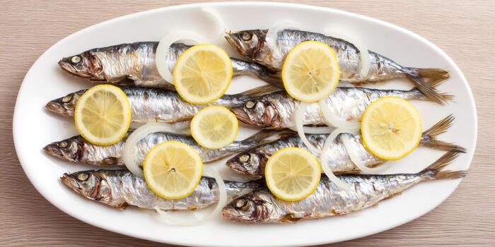 Fresh fish and lemon slices arranged on white oval plate photo