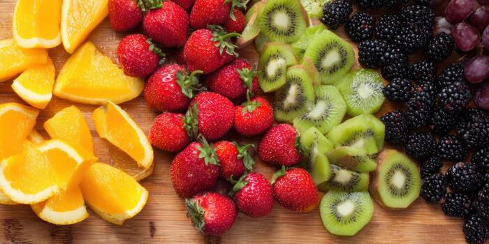 Assortment of fresh fruits oranges strawberries kiwi blackberries and grapes photo