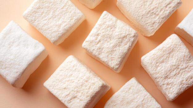 Overhead view of fluffy square shaped marshmallows on soft peach background photo