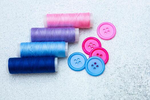 Colorful sewing threads and buttons arranged on a light surface for crafting projects photo