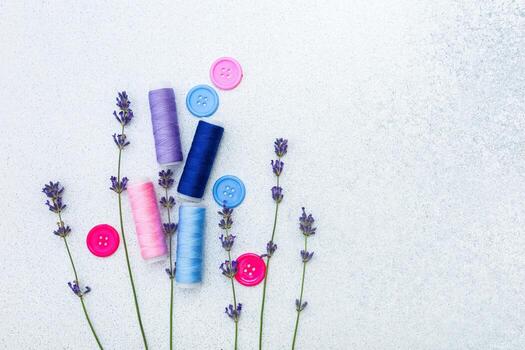 Colorful threads and buttons arranged with lavender on a soft surface photo