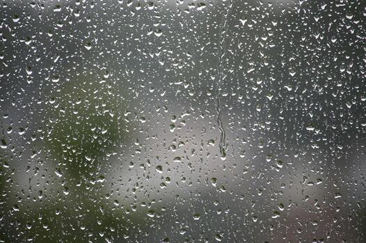 Raindrops cascade down a window, creating a beautiful, mesmerizing pattern on glass. photo