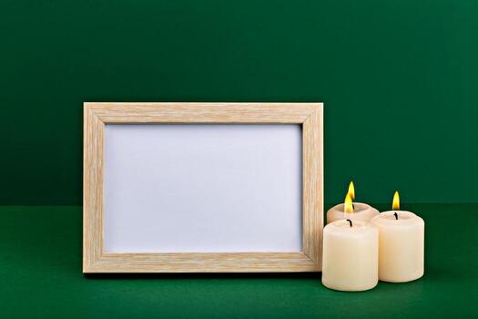 Mockup. Wooden frame mockup featuring blank space for customization, positioned next to lit candles on rich green background, creating warm and inviting atmosphere for design projects photo