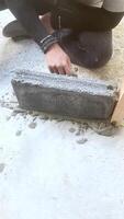 construction ouvrier pose béton blocs avec ciment mortier à bâtiment placer. fermer de mains pendant maçonnerie travail en dessous de lumière du soleil, montrant texture et bâtiment processus. video