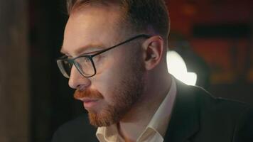 negocio hombre en oscuro oficina escritura notas en documentos mirando en computadora pantalla trabajador obsesivo trabajando con fecha límite tarea tarde hora empresario caucásico masculino chico programador a noche noche tiempo extraordinario trabajo video