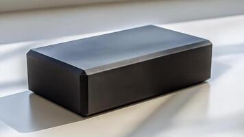 lustroso Preto retangular objeto gira lentamente debaixo brilhante luz, exibindo moderno tecnologia Projeto e minimalista estético dentro açao video