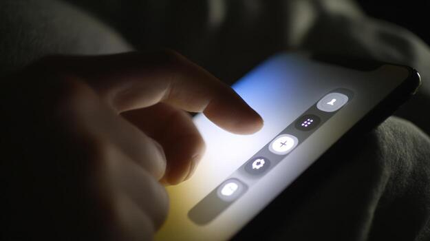 Close up of a hand interacting with illuminated smartphone screen in low light photo