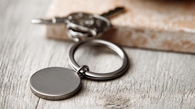 Close up of keys and keychain with blank metal tag on wooden surface photo