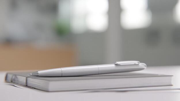 Close up of a silver pen resting on a closed notebook photo