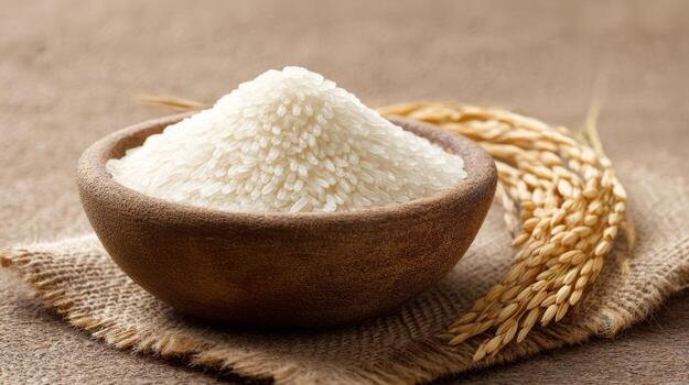 Uncooked rice is poured into a bowl, accompanied by ripe rice on a rustic surface, highlighting natural food elements photo