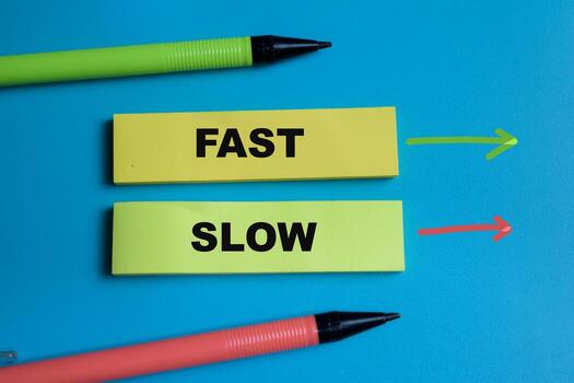 Concept of Fast or slow write on sticky notes isolated on Wooden Table. photo