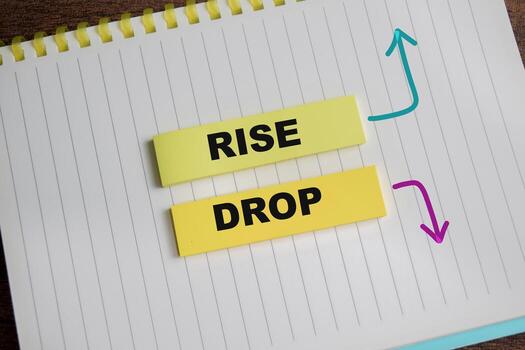 Concept of Rise and drop write on sticky notes isolated on Wooden Table. photo