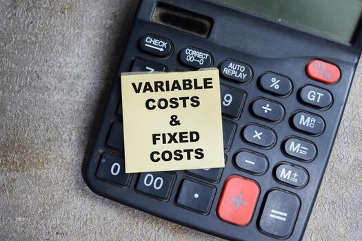Concept of Variable costs and fixed costs write on sticky notes isolated on Wooden Table. photo