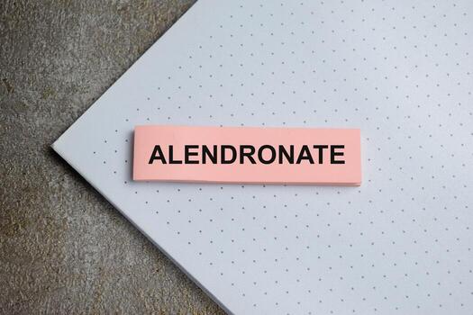 Concept of alendronate write on sticky notes isolated on Wooden Table. photo