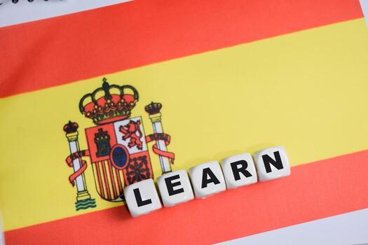 Learn on stacked wooden cubes with Spanish flag on the table. Business and finance concept photo