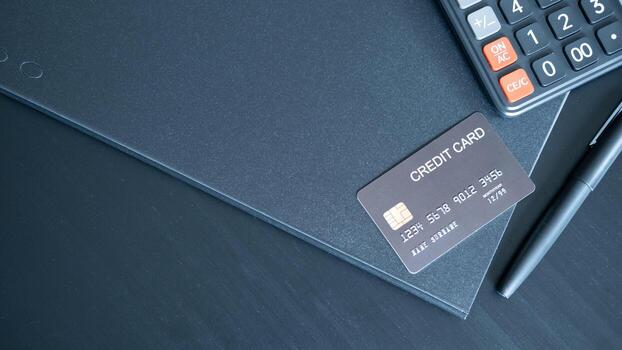 Dark themed setup with black credit card pen and calculator on folder creating professional atmosphere linked to finance credit control and business accounting. photo