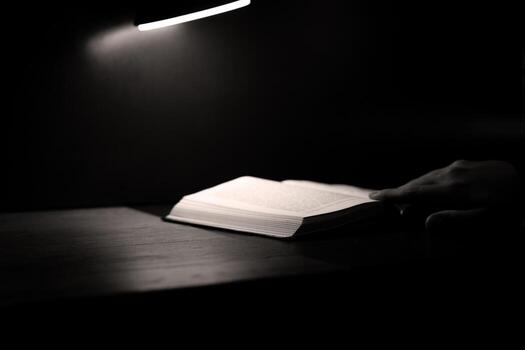 Hand gently turning pages of open book, bathed in soft. Quiet, intimate atmosphere evokes sense of reflection, deep thought, and emotional connection with content, perfect for personal discovery photo