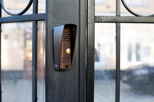 Doorbell installed on black metal gate, button clearly. Simplicity and functionality of design, perfect for topics related to home security, entrance systems and access control in residential areas photo