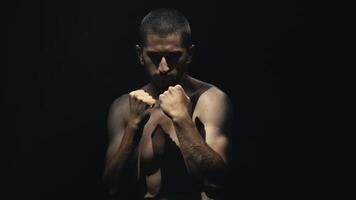 Athletic male performer showcases dynamic movement sequence, demonstrating strength and precision while executing a series of fluid arm motions against a dark backdrop. Cinematic still. video