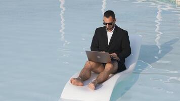 en man i en kostym arbetssätt på en bärbar dator medan Sammanträde i en slå samman. begrepp av förtroende, produktivitet, och avlägsen arbete. video