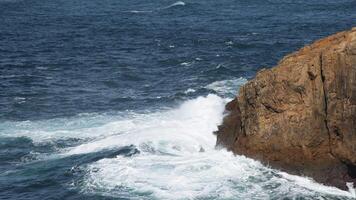 de hav kraschar mot höga klippig klippor, sändning skum in i de luft och skapande en dynamisk scen av skummig surfa och djup blå vattnen, symboliserar de vild kraft och fredlig lugn av natur. video