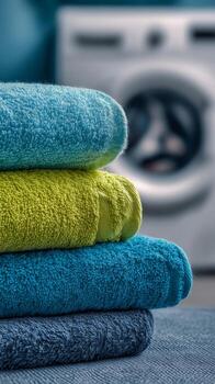 A stack of towels with a washing machine in the background photo