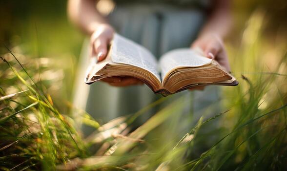 A person holding an open book in a field photo