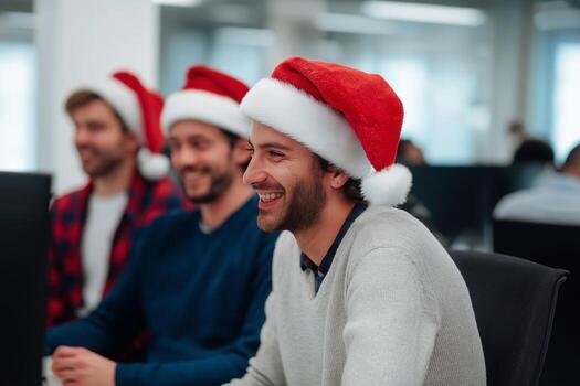 Three men in santa hats are smiling while working on computers photo