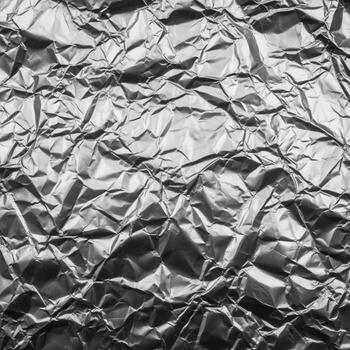 Abstract metallic texture of crumpled silver foil with sharp, defined creases and highlights photo