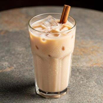 Refreshing iced chai latte with cinnamon stick and ice cubes on a textured surface photo