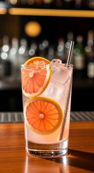 Refreshing grapefruit cocktail garnished with citrus slices and ice served at a bar with a softly blurred background photo