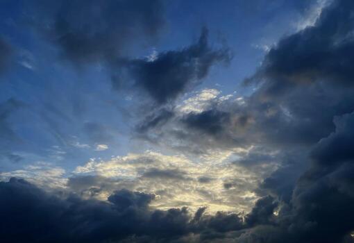 The sky is covered with dark clouds. The sky is blue on an autumn day. The sky has different layers of clouds. White clouds above, dark gray below. photo
