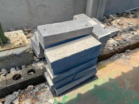 A significant pile of sturdy concrete blocks is neatly stacked on top of each other on the solid ground surface, forming a robust structure photo