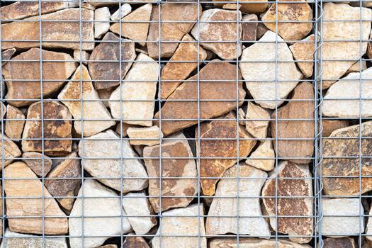 Gabion wall structure with irregularly shaped stones enclosed within a galvanized steel mesh providing a durable and decorative architectural element, highlighting a rugged and natural texture photo