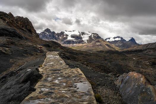 A stone path leads to a mountain range with clouds in the background photo