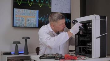An engineer checks computer components in a modern laboratory, while a technician in a white coat inspects desktop computer parts under bright lights using diagrams on screens. video