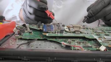 Technician testing electronic components on circuit board with precision tools, Close view of hands in black gloves using probes to check microchip performance on motherboard video