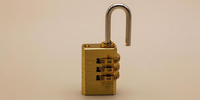 Close-up of an unlocked brass combination padlock with the shackle open, isolated on a neutral background, symbolizing access, freedom, and vulnerability photo